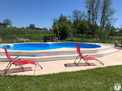 une piscine avec deux chaises rouges en face de celle-ci dans l'établissement Maison de charme à Velet avec piscine et terrasse - FR-1-583-399, à Velet
