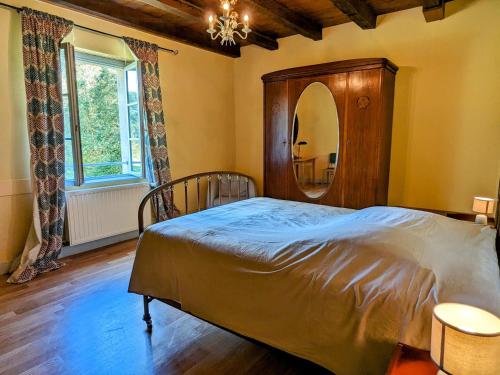 una camera da letto con un letto e un grande specchio di Maison forestière paisible avec piscine et animaux admis - FR-1-583-423 a Saint-Loup-Nantouard