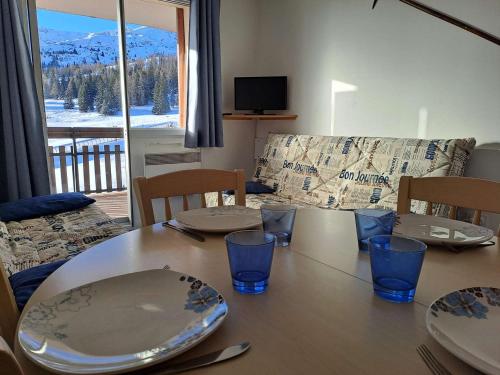 une table de salle à manger avec des assiettes et des verres dessus dans l'établissement Appartement 5 pers à 100m des pistes, parking - FR-1-525-294, à Superdevoluy