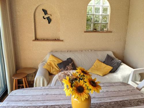 un salon avec une table avec un vase de fleurs dans l'établissement Charmante villa T2 mezzanine avec cour, jardin, véranda, barbecue et parking privé, proche plage et commerces - FR-1-797-2, à Port-la-Nouvelle