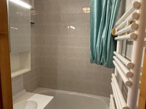 La salle de bains est pourvue d'une baignoire et d'une douche avec des rideaux bleus. dans l'établissement Studio cosy pour 4 personnes à Châtel, balcon et parking - FR-1-676-210, à Châtel