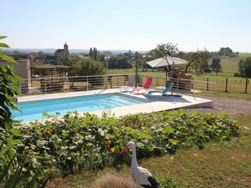a bird standing in the grass next to a swimming pool at Charmante Roulotte avec Vue Vallée de la Saône - FR-1-583-418 in Vy-le-Ferroux