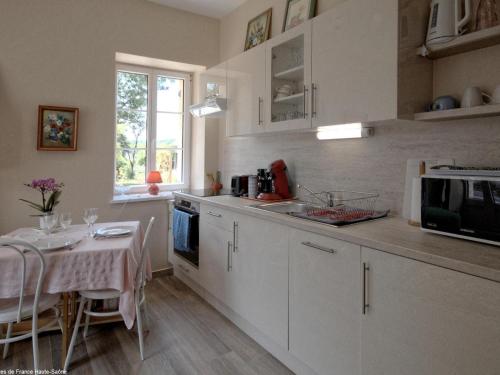 a kitchen with a table and a kitchen with white cabinets at Charmant gîte rénové avec terrasse et parking privé dans un parc, accepte petit animal - FR-1-583-433 in Montagney