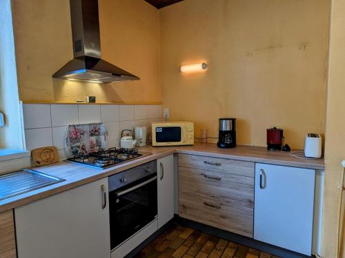 Il comprend une cuisine équipée d'une cuisinière. - un four à micro-ondes dans l'établissement Appartement charmant au pied du Plateau des Mille Etangs à Mélisey - FR-1-583-425, à Mélisey