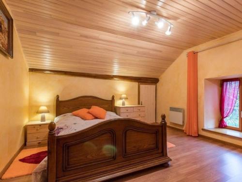 a bedroom with a wooden bed with two orange pillows at Charmante maison en pierre au cœur des Vosges - FR-1-583-436 in Saint-Bresson