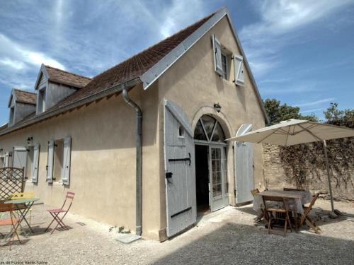 a building with an open door and a table and an umbrella at Charmant gîte rénové avec terrasse et parking privé dans un parc, accepte petit animal - FR-1-583-433 in Montagney