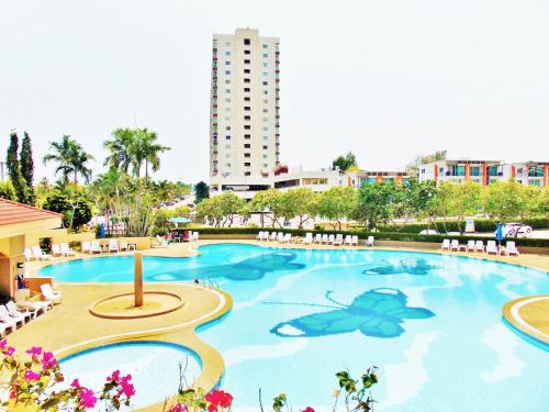 a large swimming pool with chairs and a building at Sea View Beachfront Condos Pattaya Jomtien Beach in Jomtien Beach