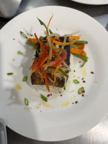 a white plate with a piece of food with vegetables on it at Sommerville Resorts in Negril