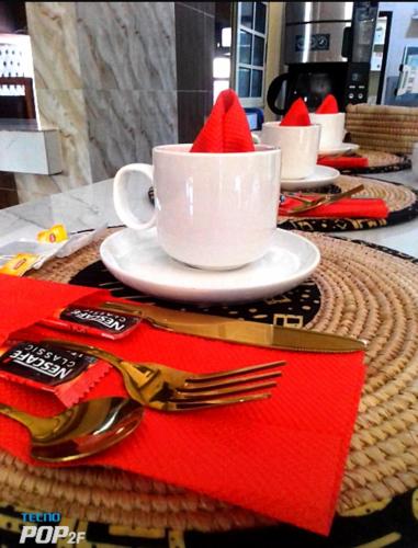 a table with three cups and a plate with a red napkin at ASVA BEACH Resort in Grand-Popo