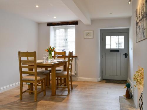 a dining room with a wooden table and chairs at Cooper Cottage in Addingham
