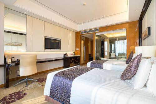 a hotel room with two beds and a desk at New Century Grand Hotel Siyang in Siyang