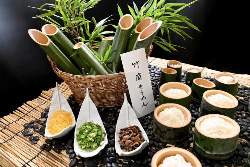 a table topped with bowls of food and a basket of plants at Sansuikan Kawayu Matsuya in Hongu
