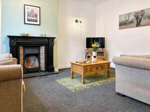 a living room with a fireplace and a tv at Lavender Cottage in Keswick