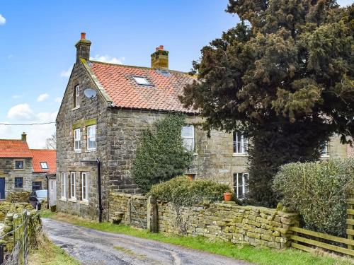 an old stone house with a stone wall at Gable End Cottage in Goathland