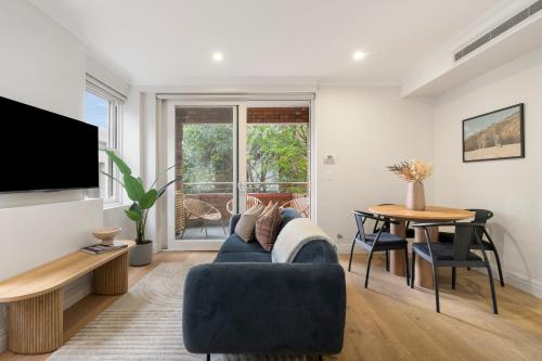 a living room with a blue couch and a table at Urban Rest Double Bay Beach in Sydney