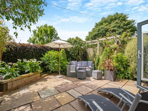 a patio with two chairs and an umbrella at Perkins Cottage in Ashover