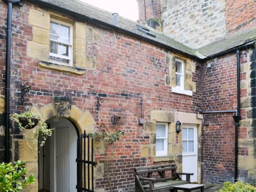 an old brick building with a gate and a bench at Dorothy Forster Court in Alnwick