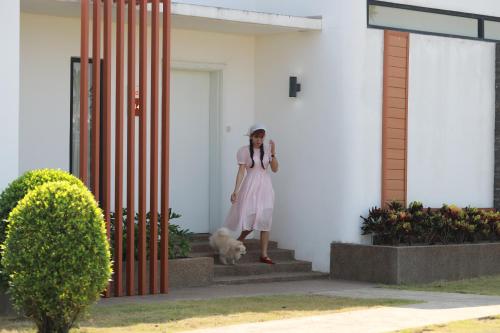 a woman in a white dress walking a dog at Wonderland Suites and Resort in Sihanoukville
