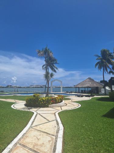a walkway in a park with palm trees and the ocean at Condo Azul in Cancún