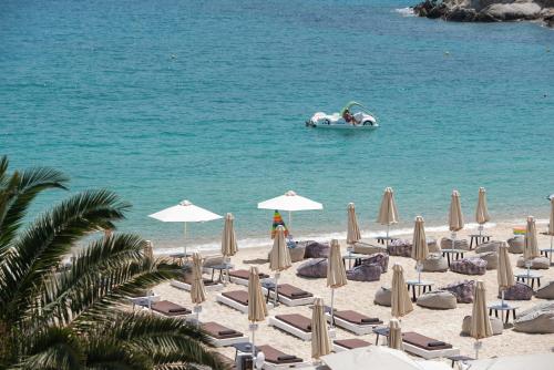 a beach with chairs and umbrellas and a boat in the water at Suite di Lusso in Kalamitsi