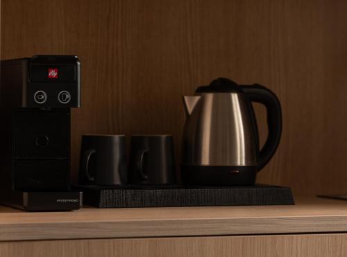 a tea kettle and two cups on a counter at Suite di Lusso in Kalamitsi