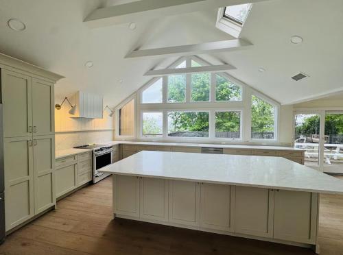 a large kitchen with white cabinets and a large island at Beachfront Mansion + Pool in Shoreham