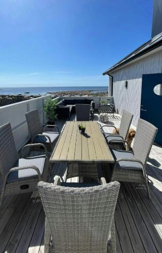 a wooden table and chairs on a deck with the ocean at Modern Holiday Home With Sea View In Borhaug in Borhaug
