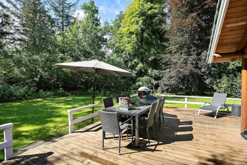 a table and chairs with an umbrella on a deck at Log Cabin Near Mariager Fjord in Hadsund