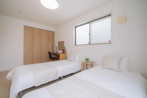 two beds in a room with a desk and a window at Comfort Miyabi-1号棟- in Yomitan