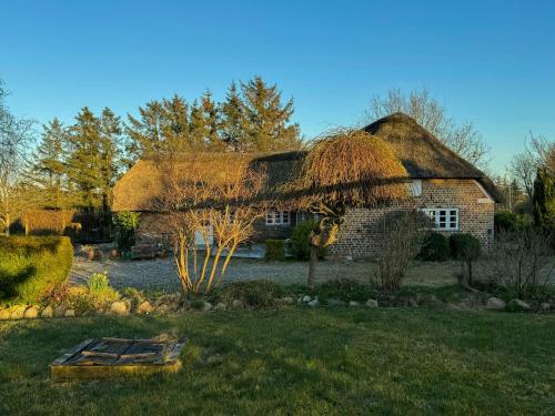 a house with a thatched roof with a garden at Historic Thatched House From 1750 In Husby in Ulfborg
