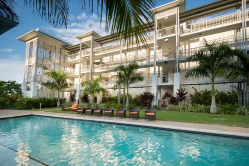 a building with a swimming pool in front of a building at Marina Waterfront Living at Port of Airlie in Airlie Beach
