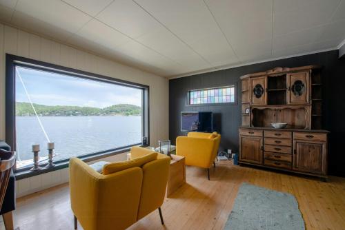 a living room with yellow chairs and a large window at Sea View And Idyll In Charming Island Cabin in Brevik
