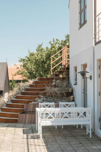 two white benches sitting outside of a building with stairs at Enjoy Sea Views In This Skagen Beach Summer House in Skagen