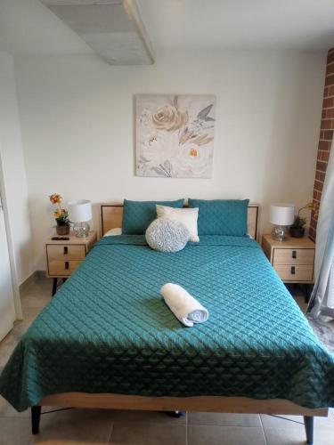 a bed with a green comforter and a pillow on it at Executive Studio Apartment Zone 10 with Parking in Estación Pamplona