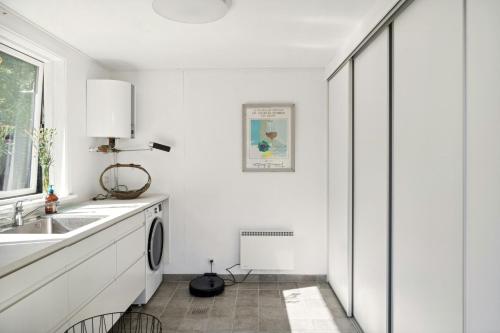 une cuisine blanche avec un évier et un lave-vaisselle dans l'établissement Enjoy Outdoor Life With Orangery And Kitchen, à Græsted