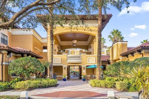 a large yellow building with trees in front of it at Resort Style Condo 4 miles from Disney in Orlando