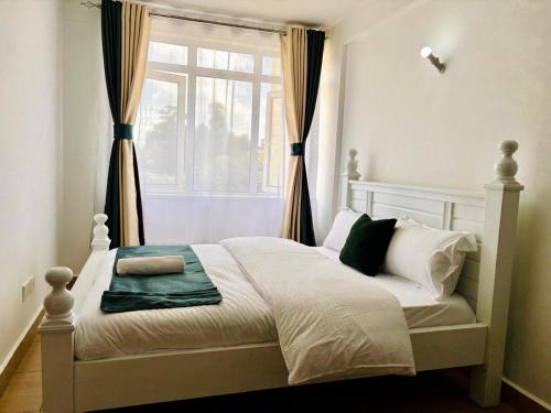 a bedroom with a bed with a window with curtains at Lina Apartment in Nairobi
