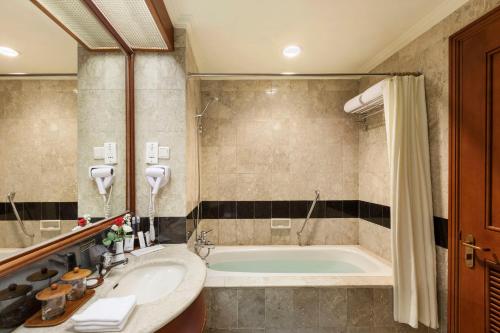 a bathroom with a tub and a sink at Prime Plaza Hotel Purwakarta in Cikampek