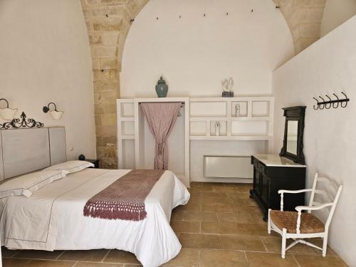 a bedroom with a bed and a chair in a room at Masseria Spartivento in Conca Specchiulla