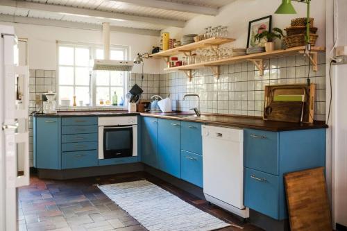 a kitchen with blue cabinets and a white appliance at Summer House For The Big Family Close To The Fjord in Agger