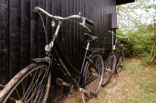 two bikes parked next to a black wall at Tiny House Vibe At Beach Near Saksild Home in Odder
