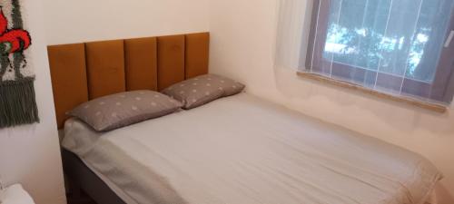 a bed with two pillows and a window in a room at Rest Plus More in Pula