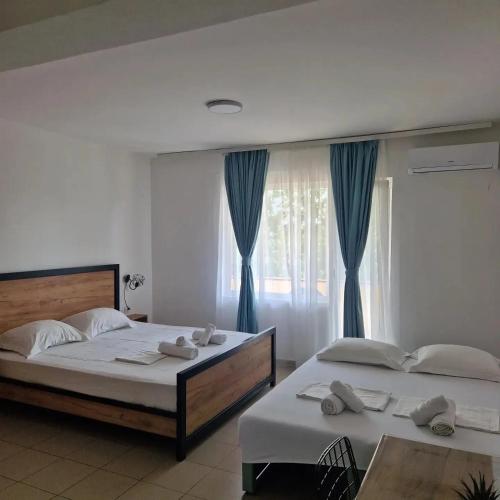 a bedroom with two beds and a window with blue curtains at Apartmani Naumovi 2 in Star Dojran