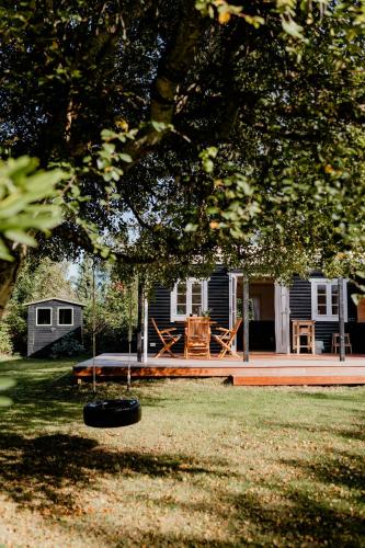 a house with a porch and a picnic table in the yard at Cottage Life In Intimate Wooden Cabin in Dronningmølle