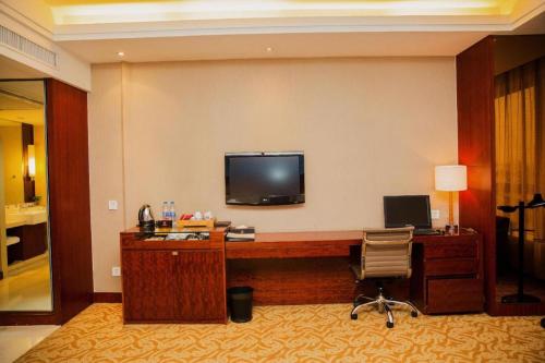 a hotel room with a desk and a television on the wall at Jinhua World Trade Hotel in Jinhua