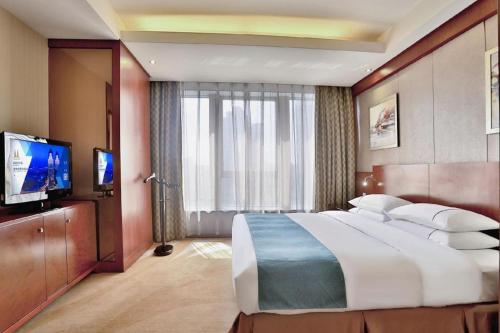 a bedroom with a large bed and a flat screen tv at Jinhua World Trade Hotel in Jinhua
