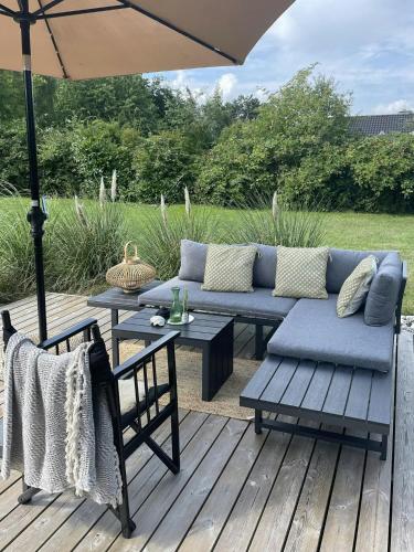 a patio with a couch and a table and an umbrella at Summerhouse With Hot Tub On Langeland in Tranekær