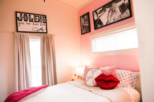 a bedroom with pink walls and a bed with red pillows at Little Dolly (In The Pines at KY Lake) 105 Pine Grove Lane, Dover, TN 37058 in Dover