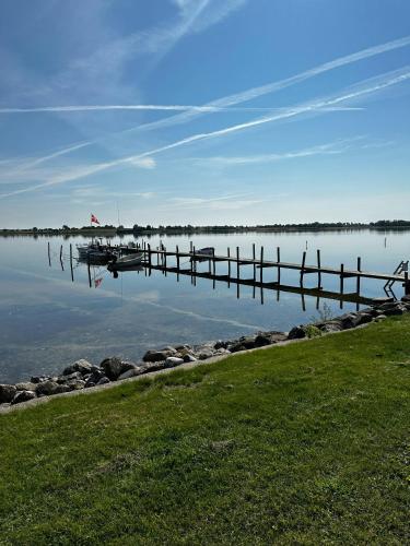 a dock on a lake with a boat on the water at Fjord-Side Cottage In Munkebo By The Water in Munkebo