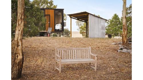 a wooden bench sitting in a yard with a building at Grampians Views Moyston by Tiny Away in Moyston